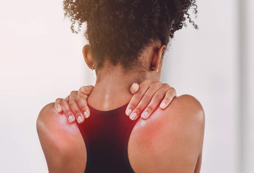 Can bra cause back pain: close up of a woman rubbing her shoulders, while her shoulders are red, signifying pain