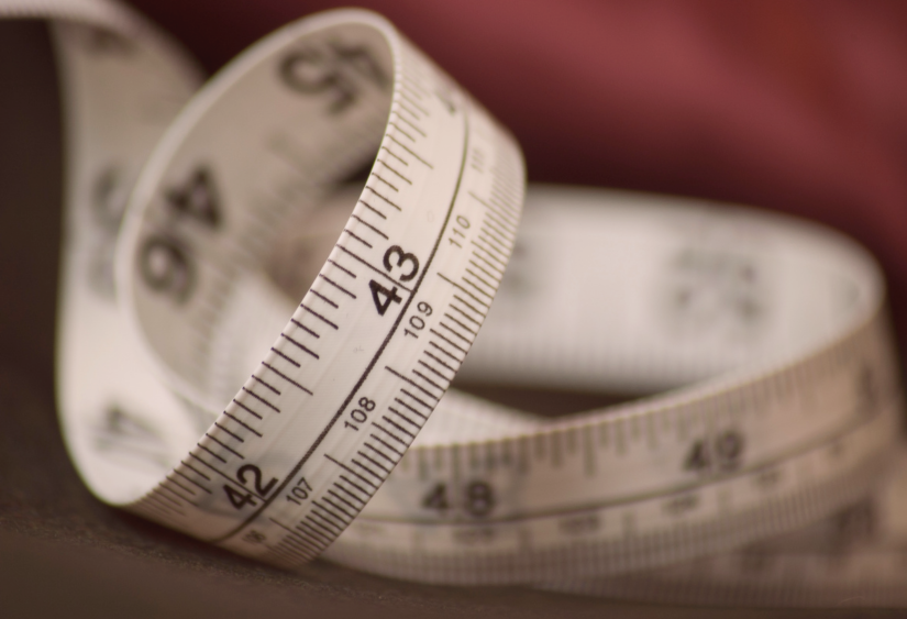 How bra size is measured, an image of a soft measuring tape coiled against fabric