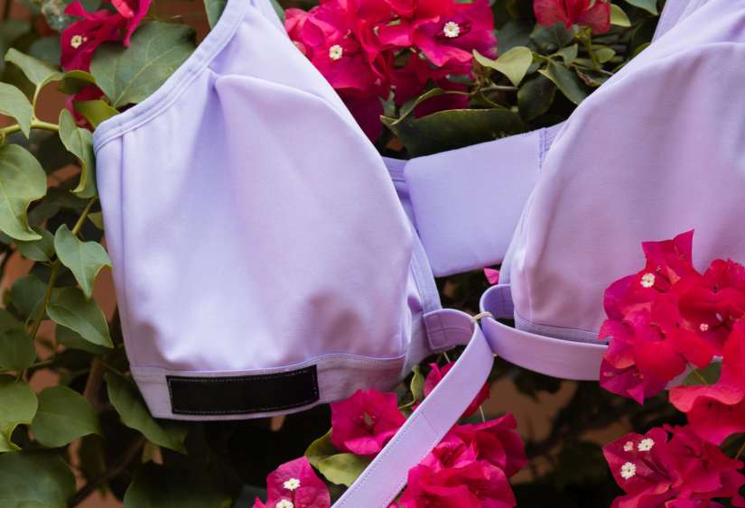 Adaptive bra in lilac laying on flowers and showcasing the velcro front closure